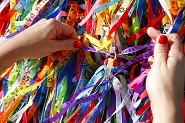 Woman tying lucky ribbon at Igreja Nosso Senhor do Bonfim church, Salvador (Salvador de Bahia), Bahia, Brazil, South America 