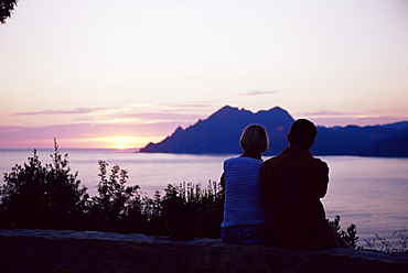 Couple watching sunset near Porto, Corsica, France, Mediterranean, Europe