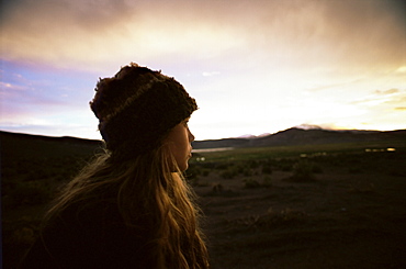 Girl looks at the Andes as the sun sets, Isluga National Park, Chile, South America