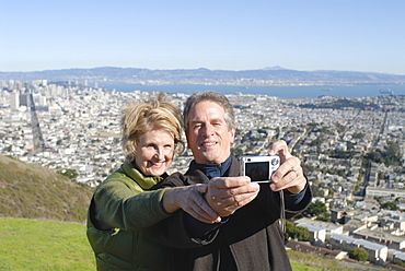 Married couple take photo of themselves, with downtown San Francisco beyond, California, United States of America, North America