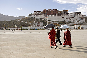 Monks carrying umbrellas to shield against the sun, in front of the Potala Palace, UNESCO World Heritage Site, Lhasa, Tibet, China, Asia