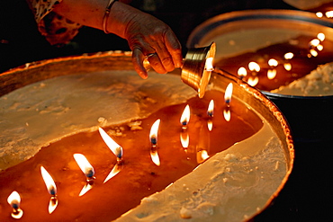 Pilgrims pour melting butter from their lamps into the yak butter lamps in the monastery, topping them up continually, Lhasa, Tibet, China, Asia
