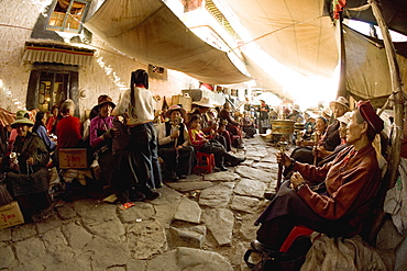 Pilgrims spin prayer wheels outside a monastery in the Bharkor, Lhasa, Tibet, China, Asia