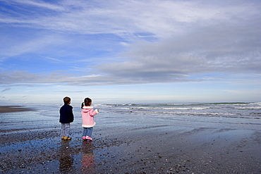 Boy aged four and girl aged three on a black volcanic sand beach in Manawatu, North Island, New Zealand, Pacific