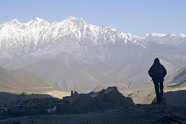 Trekker at dawn looking out over the old fortified village of Jharkot on the Annapurna circuit trek, the valley below is supposedly the deepest in the world with Annapurna on one side and Dhaulagiri on the other, Nepal, Asia