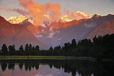 Sunset, Lake Matheson, with Mount Tasman and Mount Cook behind clouds, Westland Tai Poutini National Park, UNESCO World Heritage Site, West Coast, Southern Alps, South Island, New Zealand, Pacific