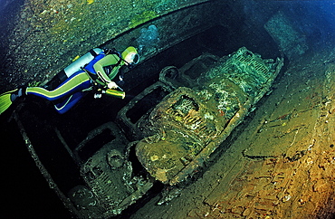 Scuba diver looking at military cars whilst diving on Umbria shipwreck, Wingate Reef, Sudan, Red Sea, Africa