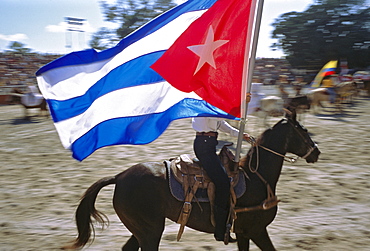 A horseback rider carries the Cuban flag in the opening ceremony of a rodeo in Havana, Cuba