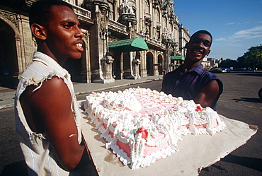 Young men carrying a huge cake across the Paseo de Marti in Havana, Central Habana, Havana, Cuba