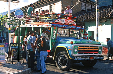 Banos resort and famous hot springs and site of Basilica of Senora de Agua Santa teens on street boarding a local bus, Highlands, Ecuador