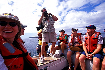 Tourists on an eco-tourism excursion in an inflatable tender near the beach at Punta Pitt on San Cristobal Island, Galapagos Islands, Ecuador