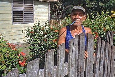 A man standing in his garden in front of his home located in the rural town of Baracoa in eastern Cuba, Cuba