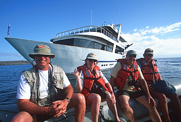 Eco-tourists coming from scuba diving boat for land excursion to see sea lions on Mosquera Island near Bartolome Island, Galapagos Islands, Ecuador