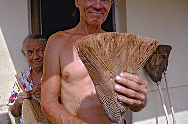 A broom maker displaying one of his handmade, brooms made from coconut fibers in the town of Baracoa in eastern Cuba, Cuba