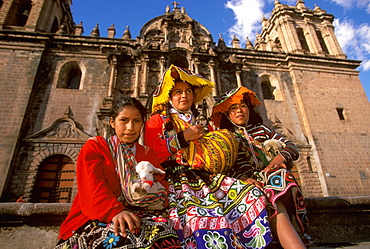 Ancient capital of the Incas the Plaza de Armas with young girls in traditional dress on the steps in front of the Cathedral, Cuzco, Highlands, Peru