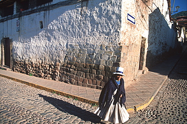 Quechua Indian woman crossing street in front of a colonial building with Incan foundations near the Plaza de Armas, Cuzco, Highlands, Peru