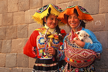 Two young Indian girls in traditional dress in front of a finely cut Inca Wall on Calle Loretto in the heart of the colonial center, Cuzco, Highlands, Peru