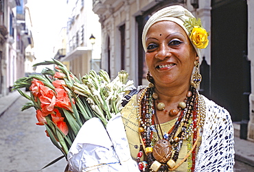 Portrait of a Cuban women with flowers and jewelry walking on a street in Habana Vieja, Cuba