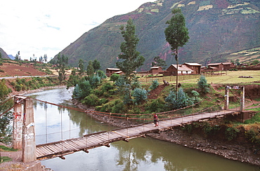 The Sacred Valley of the Incas with a suspension bridge crossing the Urubamba River outside the town of Huasaq, Highlands, Peru