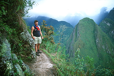 Machu Picchu the ancient Incan city in the Vilcabamba Mountains hiker on trail to the top of Huayna Picchu Mountain, Highlands, Peru