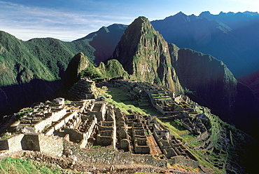 Machu Picchu view of the ancient city with Huayna Picchu Peak above the Rio Urubamba terraces, city walls and gate in foreground, Highlands, Peru