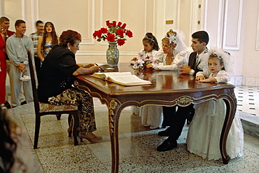 A bride and groom and their wedding party at their civil wedding ceremony in the Palacio de los Matrimonios in Centro Habana, Havana, Cuba