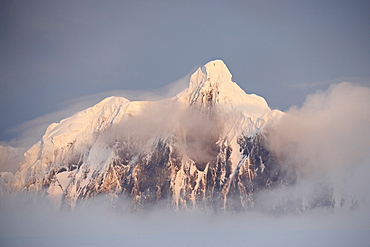 Snow covered mountain at sunset, generating its own fog cover, Wiencke Island, Antarctic Peninsula, Antarctica, Polar Regions