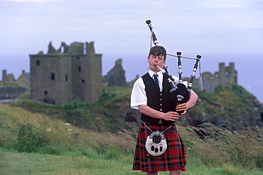 Piper playing, in front of Dunnotar Castle dating from the 14th century, near Stonehaven, Aberdeenshire, Scotland, United Kingdom, Europe