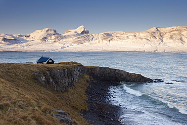 Small house and Borgarfjordur Eystri fjord, Mount Dyrfjoll (Door mountain), 1136m, in background, East Fjords, Iceland, Polar Regions