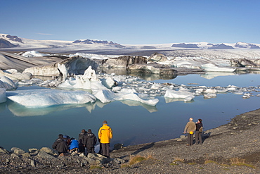 Tourists viewing icebergs in Jokulsarlon glacial lagoon, Oraefajokull glacier in the distance, East Iceland, Iceland, Polar Regions