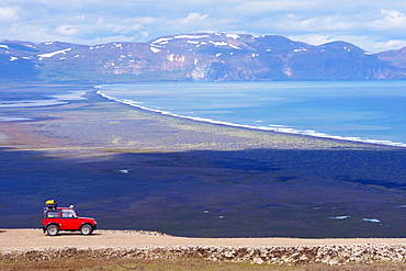 Red 4x4, Heradsfloi Bay and Hlidarfjoll mountains in background, in the north of the East Fjords region (Austurland), Iceland, Polar Regions