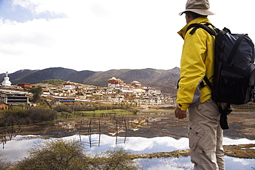 Chinese man trekking and looking at Ganden Sumsteling Gompa (Gandan Sumtseling) (Songzanlin Si) Buddhist Monastery, Shangri-La, formerly Zhongdian, Yunnan Province, China, Asia