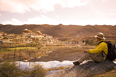 Chinese man trekking and looking at Ganden Sumsteling Gompa (Gandan Sumtseling) (Songzanlin Si) Buddhist Monastery, Shangri-La, formerly Zhongdian, Yunnan Province, China, Asia