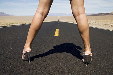 Woman in high heels on empty road, Death Valley National Park, California, United States of America, North America