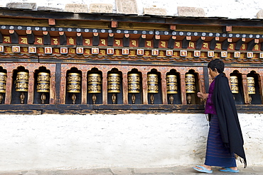 Bhutanese woman turning Buddhist prayer wheels, Trashi Chhoe Dzong, Thimphu, Bhutan, Asia