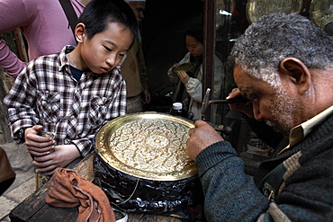 Tourists watch an engraver in the great bazaar of Khan al-Khalili, Cairo, Egypt, North Africa, Africa