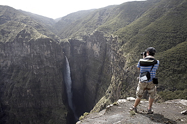 A tourist photographs a waterfall at the Geech Abyss, in the Simien Mountains National Park, Ethiopia, Africa