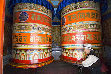 Old woman pushing prayer wheels, Jingang Si, Kangding, Sichuan, China, Asia