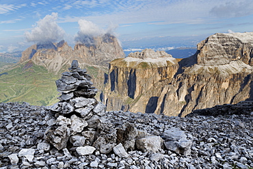 Stone cairn on Sass Pordoi mountain in the Dolomites near Canazei, with cloud covered Sassolungo mountains in the distance, Trentino-Alto Adige, Italy, Europe 