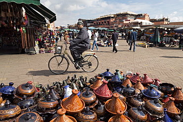 Cyclist passing a stall selling traditional clay tajine cooking pots in Place Jemaa el-Fna, Marrakesh, Morocco, North Africa, Africa