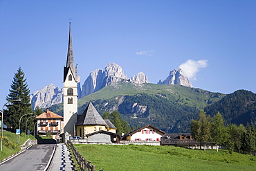 A church in the village of Alba with the rugged peaks of the Sassolungo in the distance, Dolomites, Italy, Europe