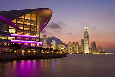 Hong Kong Convention and Exhibition centre illuminated at dusk with the International Finance Centre building and financial district in the background, Hong Kong, China, Asia