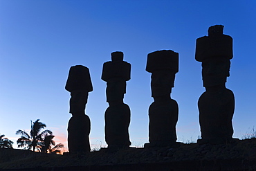 Anakena beach, monolithic giant stone Moai statues of Ahu Nau Nau, four of which have topknots, silhouetted at dusk, Rapa Nui (Easter Island), UNESCO World Heritage Site, Chile, South America