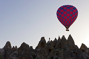 Hot air balloon taking off with tourists on board for a flight over the famous volcanic tufa rock formations around Goreme, Cappadocia, Anatolia, Turkey, Asia Minor, Eurasia