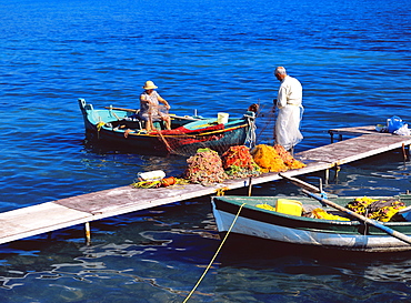 Fisherman and his wife cleaning the fishing nets in boat and jetty, Corfu, Greek Islands, Greece, Europe