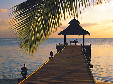 Couple looking at sunset on a jetty, Maldives, Indian Ocean, Asia