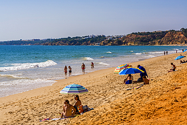 Beachgoers at Red sandstone cliffs of Praia da Falésia, Albufeira district, souther, portugal