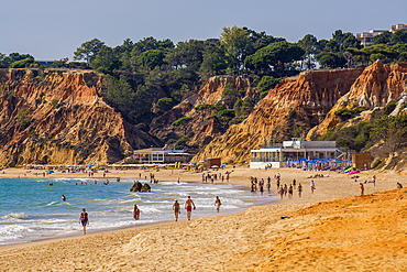 Beachgoers at Red sandstone cliffs of Praia da Falésia, Albufeira district, souther, portugal