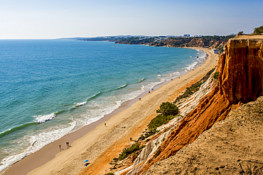 Beachgoers at Red sandstone cliffs of Praia da Falésia, Albufeira district, souther, portugal