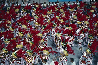 BRAZIL  Rio de Janeiro Carnival procession of dancers wearing red feathered head dresses Brasil